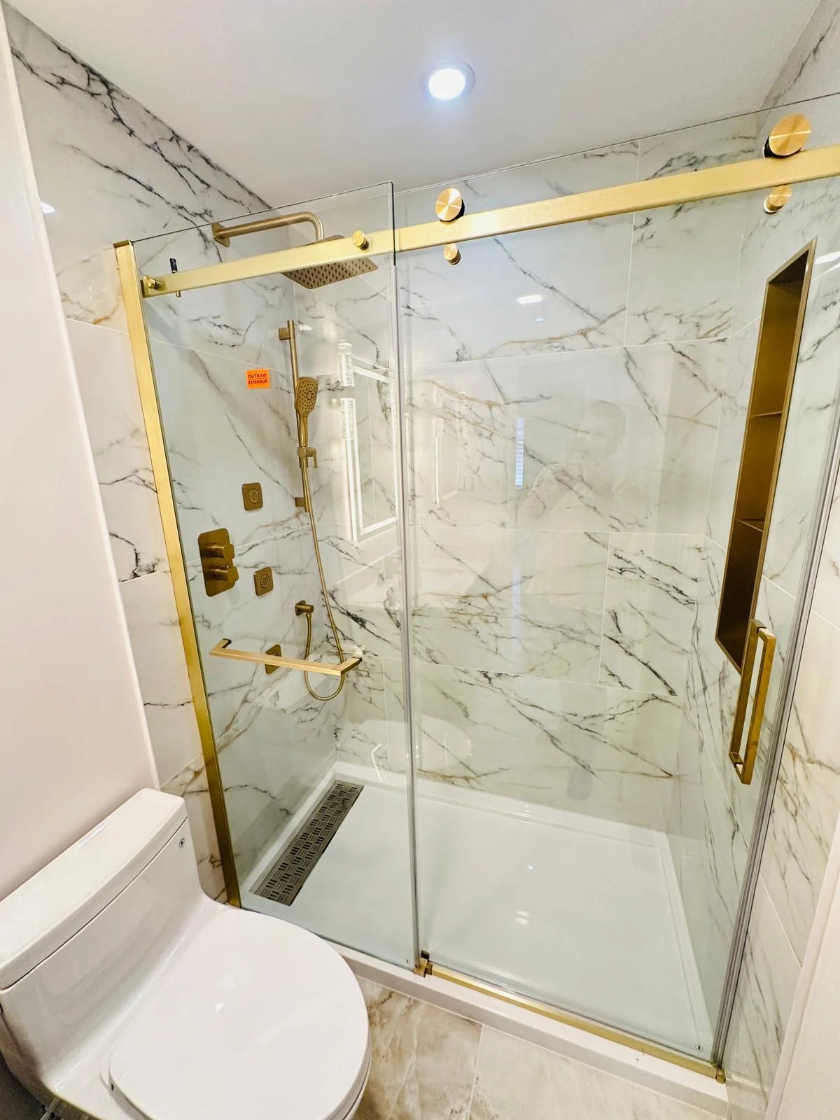 Luxury marble shower with gold fixtures and glass door