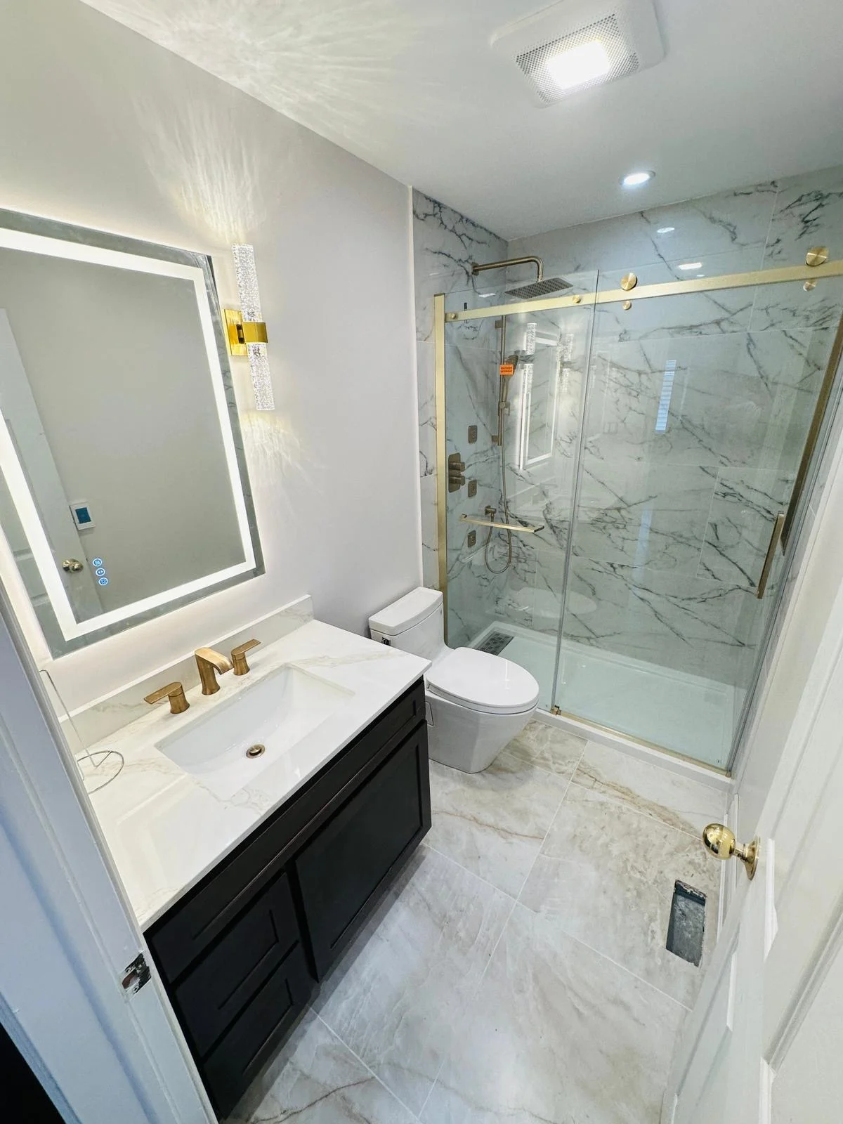 Finished bathroom with marble shower tile and gold fixtures