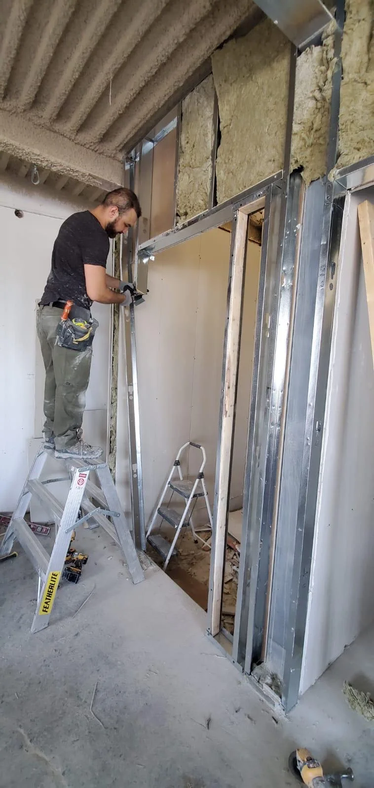 Steel stud framing and drywall board installation with insulation visible